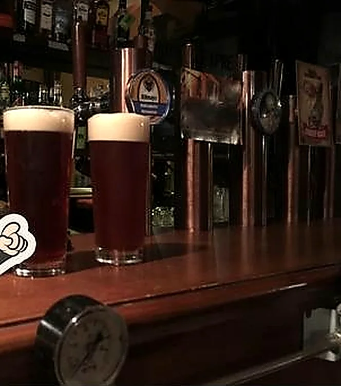 Tre pinte di birra scura appena spillate sul bancone di legno, accanto alle colonne di rame.