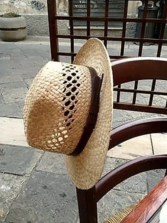 Un cappello di paglia appoggiato allo schienale di una sedia, ai tavoli fuori dal locale.