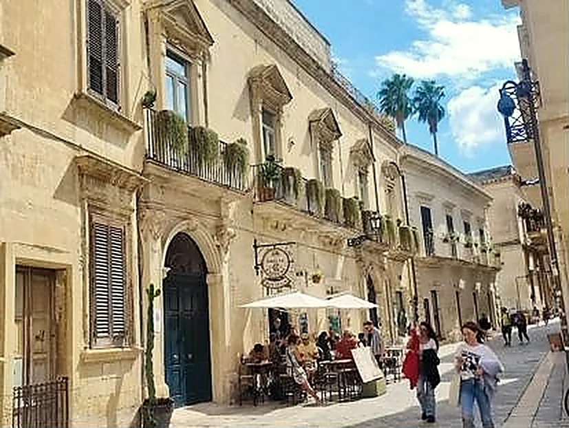 I tavoli all'aperto sotto l'ombrellone bianco, davanti a un palazzo barocco di Via Palmieri.