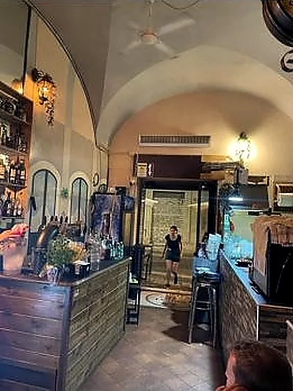 La sala a volte con il bancone di legno e le bottiglie sullo scaffale.